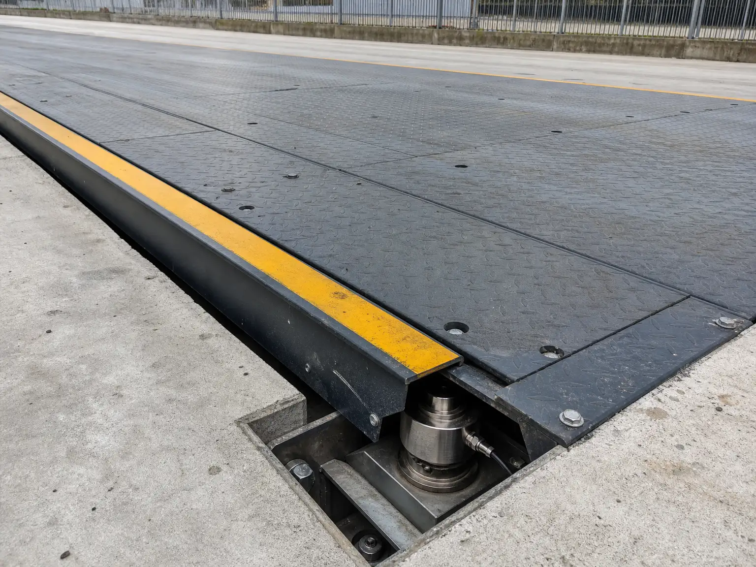 Flush-mounted steel weighbridge deck with an inspection pit exposing a stainless load cell